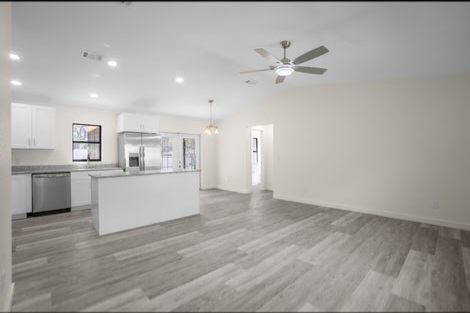 Gray luxury vinyl plank (LVP) flooring in an open-concept living room and kitchen with vaulted ceiling in Inverness, FL