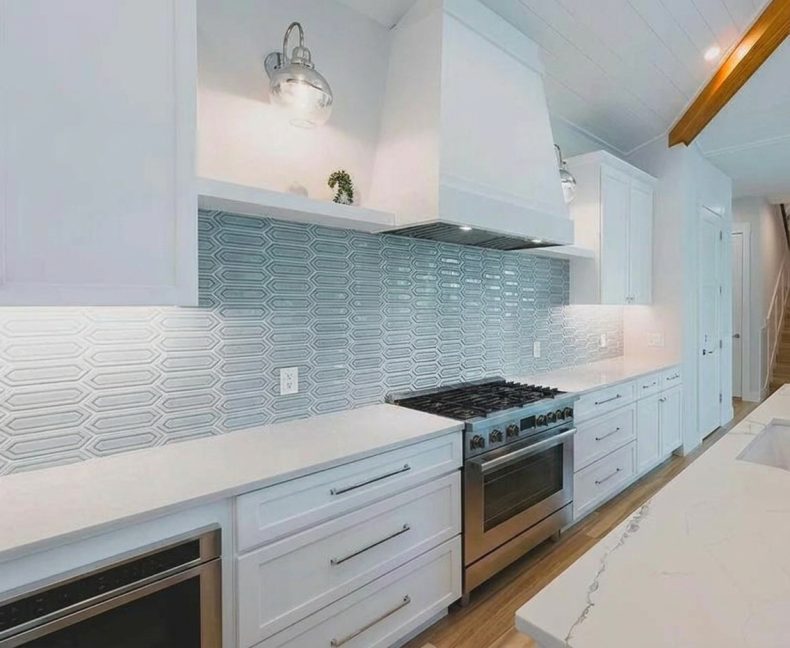 Blue picket tile kitchen backsplash with white shaker cabinets, quartz counters and a custom range hood in Anna Maria Island, FL