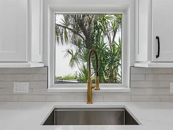 Kitchen tile backsplash installation with gold faucet and window in Treasure Island, FL